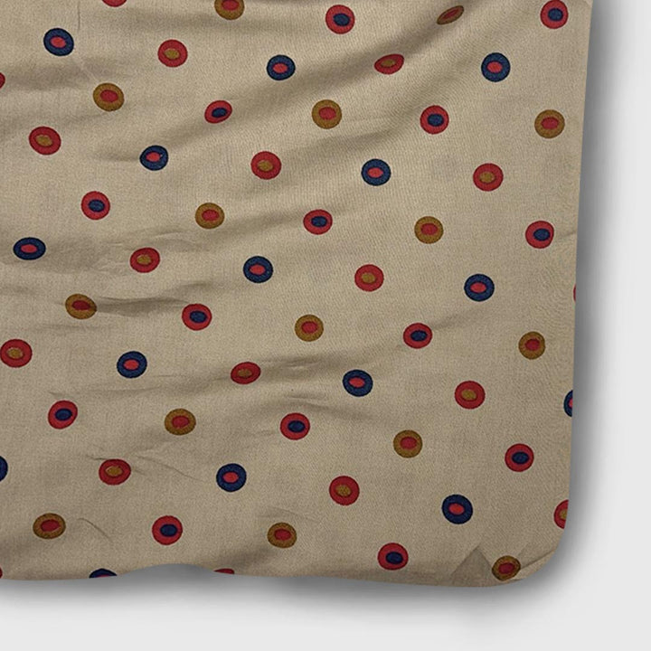 Cream muslin fabric featuring multi-shaded dots in red and blue