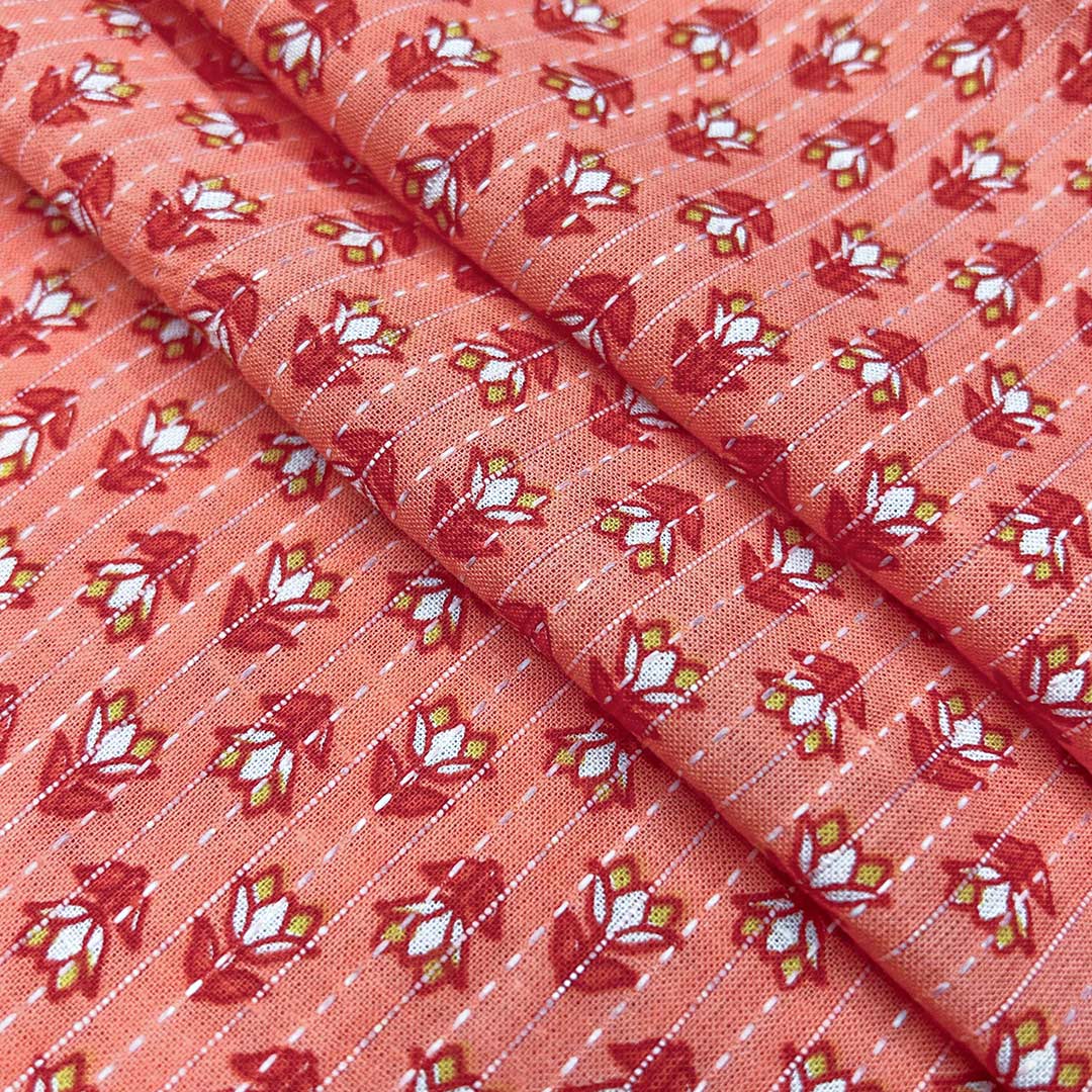 Soft pinkish-orange cotton fabric adorned with small floral Kantha stitching, offering a touch of artisanal beauty at Fabrics @StudioLCX.