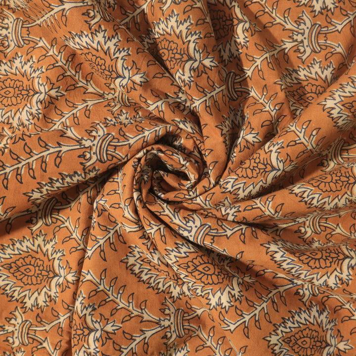 Vibrant orange cotton fabric elegantly twisted, showcasing detailed floral Dabu hand block prints for distinctive design at Fabrics @StudioLCX.