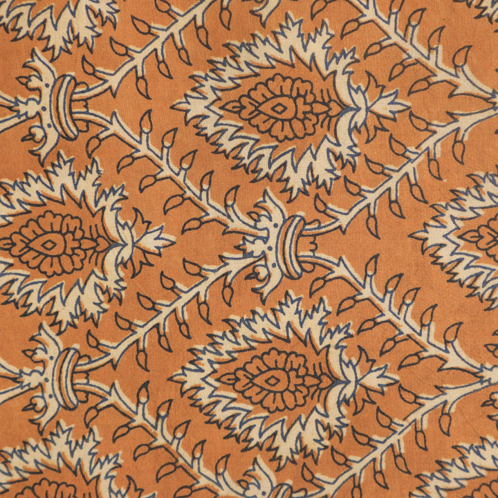 Vibrant orange cotton fabric elegantly twisted, showcasing detailed floral Dabu hand block prints for distinctive design at Fabrics @StudioLCX.