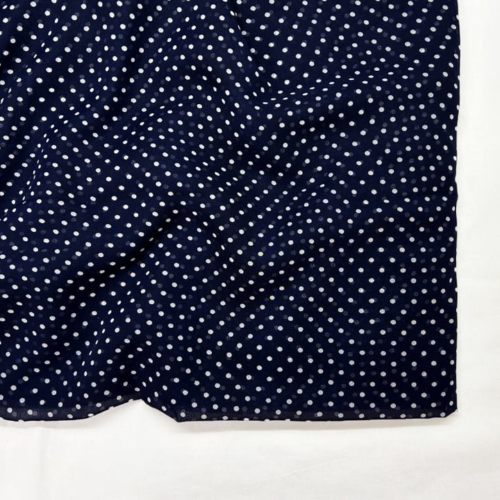 Stylish navy blue georgette fabric with playful white polka dots available at Fabrics @StudioLCX for fashionable attire.