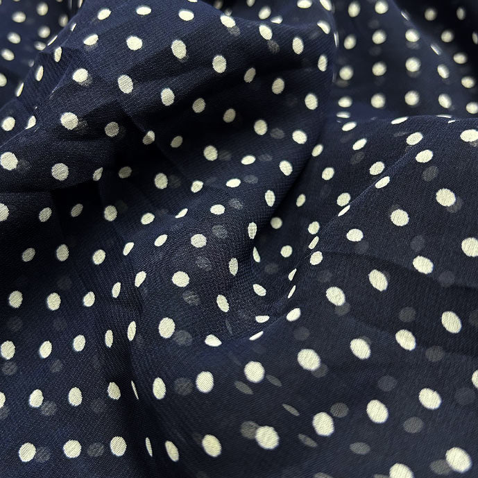 Stylish navy blue georgette fabric with playful white polka dots available at Fabrics @StudioLCX for fashionable attire.